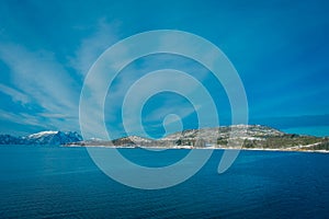 Beautiful outdoor view of coastal scenes of huge mountain covered with snow on Hurtigruten voyage