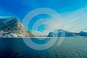 Beautiful outdoor view of coastal scenes of huge mountain covered with snow on Hurtigruten voyage