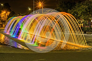 Beautiful outdoor view of colorful water entertainment structure fountain, at long exposure in the night, with buildings photo