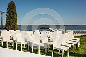 Beautiful outgoing wedding set up.Romantic wedding ceremony , wedding outdoor on the lawn water view. Wedding decor. White wooden