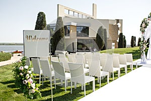 Beautiful outgoing wedding set up. Romantic wedding ceremony , wedding outdoor on the lawn water view. Wedding decor. White wooden