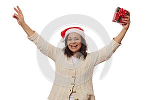 Overjoyed woman in Santa hat, holds Christmas gift in her hands, smiling looking at camera, isolated on white background