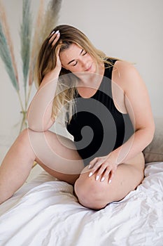 Beautiful overweight woman in black swimsuit on grey background