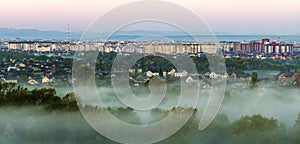 Beautiful panorama of morning aerial view of Ivano-Frankivsk city, Ukraine. Scene of quiet suburbs among green trees under dense f