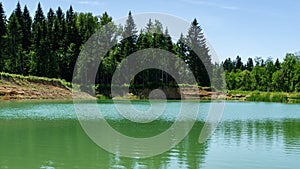 Beautiful panorama of quarry lake with emerald green water and big forest as background