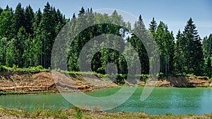 Beautiful panorama of quarry lake with emerald green water and big forest as background. Closed down quarry now is bathing plac