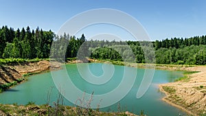 Beautiful panorama of quarry lake with emerald green water and big forest as background. Closed down quarry now is bathing place