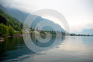 Beautiful panorama view of Geneva lake and small village on mountain and cloudy sky background