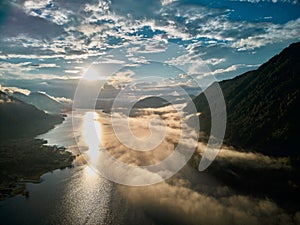 Beautiful panoramic landscape above clouds and mountains with sun rising in the middle.