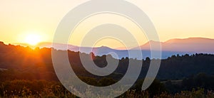 Beautiful panoramic mountain landscape with hazy peaks and foggy valley at sunset