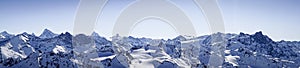 Beautiful panoramic shot of snow covered mountain ranges under a clear blue sky