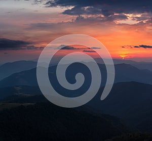 Beautiful panoramic sunset in the mountains landscape. Dramatic evening sky. Green hills covered by forest.