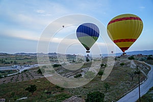 Beautiful panoramic view of colorful balloons flying above Cappadocia unique landscape ground with blue sky background at sunrise