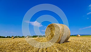 Beautiful panoramic view of a field with straw bales and a blue sky with clouds