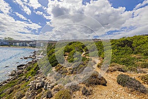 Beautiful panoramic view of rocky coast line with hotels beach and buildings on blue sky with white clouds background.