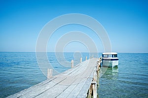 Beautiful paradise seascape, boat in turquoise clear waters near wooden beach pier