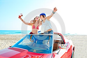 Beautiful party girls dancing in a car on the beach