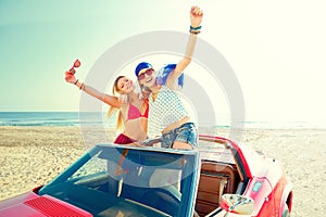 Beautiful party girls dancing in a car on the beach