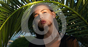 beautiful passion girl in palm leaves. young woman with Make-up under palm tree