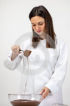 Beautiful pastry-cook pouring dark melted chocolate isolated on white background