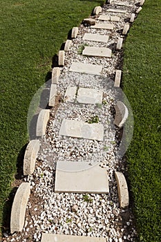 Beautiful path of white stones on a lawn of green grass.