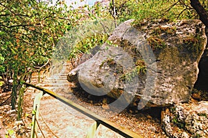 Beautiful pathway from Hell Cave to Heaven Cave. Big stones and green leave trees along the path. There`s small cave on bottom