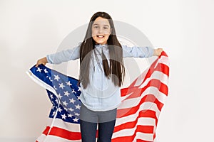 Beautiful patriotic little girl with the American flag held in her outstretched hands