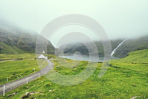 Beautiful peaceful church in Saksun valley next to the waterfall in foggy weather, Faroe Islands, North Europe, hidden gem for