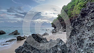 Beautiful peaceful landscape with ocean waves and dark rocks at blue hour. Wild tropical beach after sunset. Natural