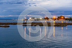 Beautiful and peaceful sunset over the small sea harbour with blue clouds and lights reflection in the water