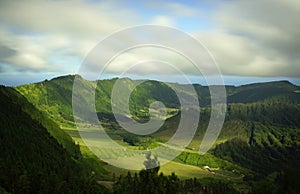 Beautiful peaceful view of valley with lush green fields and hills. Background of cloudy sky