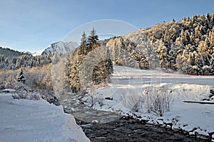 Beautiful peaceful winter landscape in the Frence Alps, at one of the ski stations, France. Mountain river at the forefront