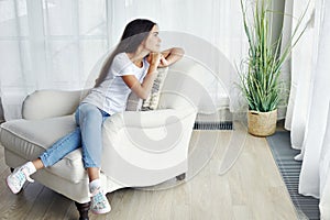 Beautiful pensive preteen 12s girl sit on armchair