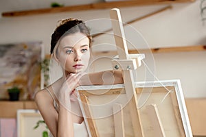 beautiful pensive young artist leaning at easel