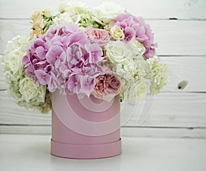 Beautiful peonies in the pink box with fruits on wooden background