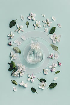 Beautiful perfume bottles and spring flowers on blue background