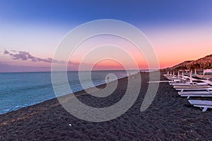 Perissa, beach at sunset, Santorini, Greece with beautiful beach huts, blue sky and clouds