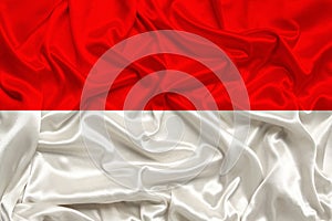 Beautiful photo of the national flag of Monaco and Indonesia on delicate shiny silk with soft draperies, the concept of state