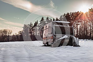 Beautiful photo of old and abandoned caravan in the middle of snow covered meadow in Winter time. Illuminated Caravan campervan
