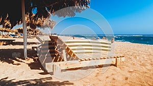 Beautiful photo of old wooden sun beds or loungers on the empty beach at sunny windy day