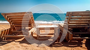 Beautiful photo of old wooden sun beds or loungers on the empty beach at sunny windy day
