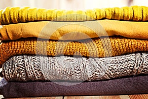 Beautiful photo of a pile of knitted yellow woman sweaters. Woman fashion. Autumn clothing.