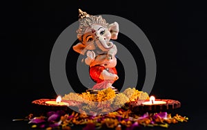 Beautiful photography of ganpati statue with two glowing lamp and flowers on the black background. hinduism concept