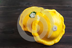 Beautiful picture of vegetables. Focus on two young squash pathes. Patiosons on a dark wooden background close-up. Textur