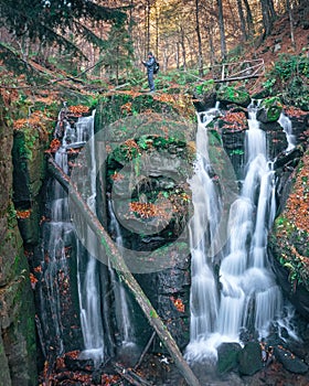 Beautiful picturesque waterfall Vojvodin Voevodin in the Ukrainian carpathians forest Voievodyn, tourist traveler with a backpack