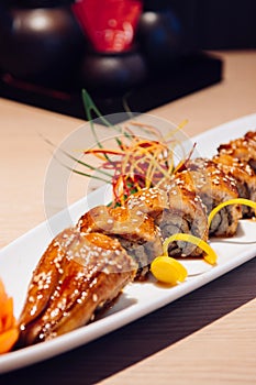 Japanese grilled Unagi Maki roll on white plate dark background