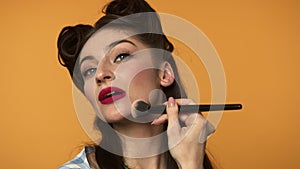 Beautiful pin up girl applying makeup foundation with smile