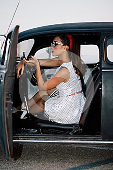 Beautiful pin-up girl inside vintage car