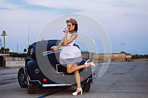 Beautiful pin-up girl posing with hot road car