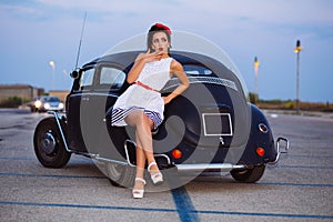 Beautiful pin-up girl posing with hot road car